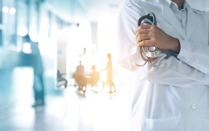 Doctor with stethoscope in hand; patients in background