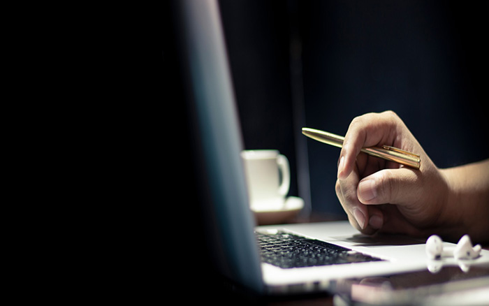 Person with laptop and pen in hand